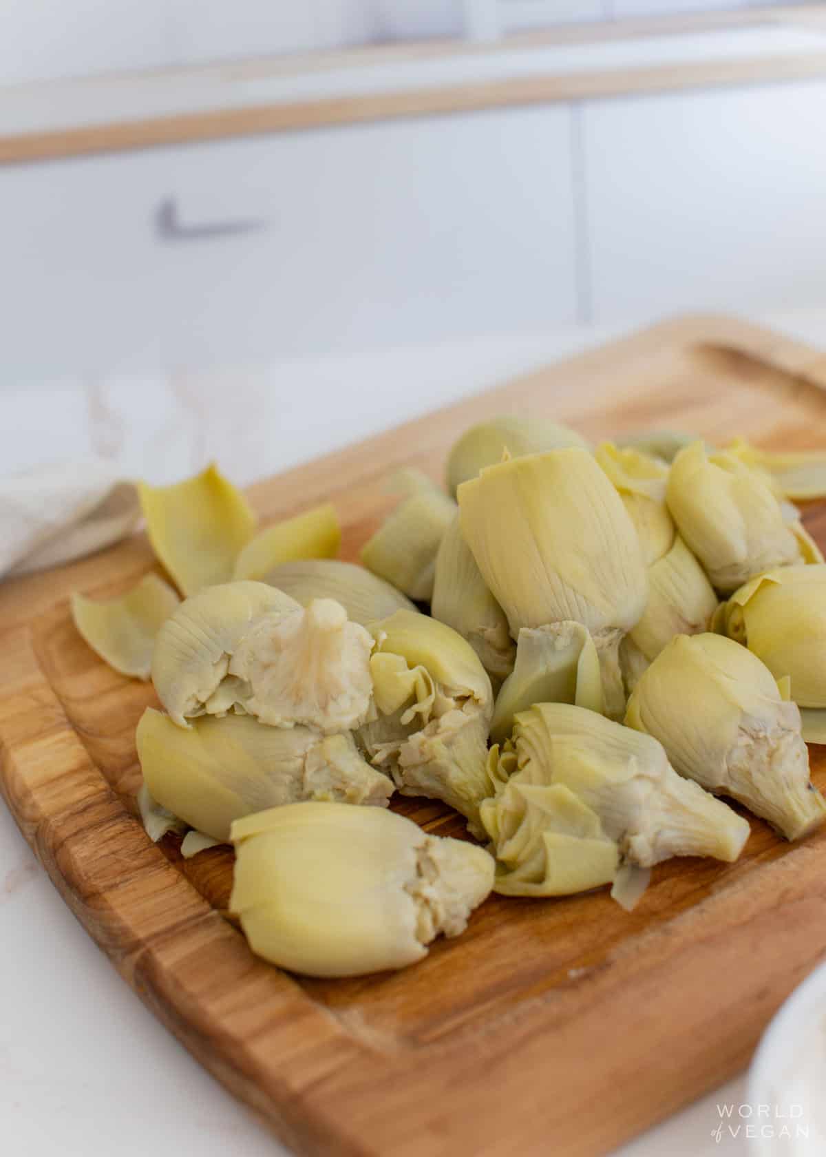 whole artichoke hearts on a cutting board from a can drained