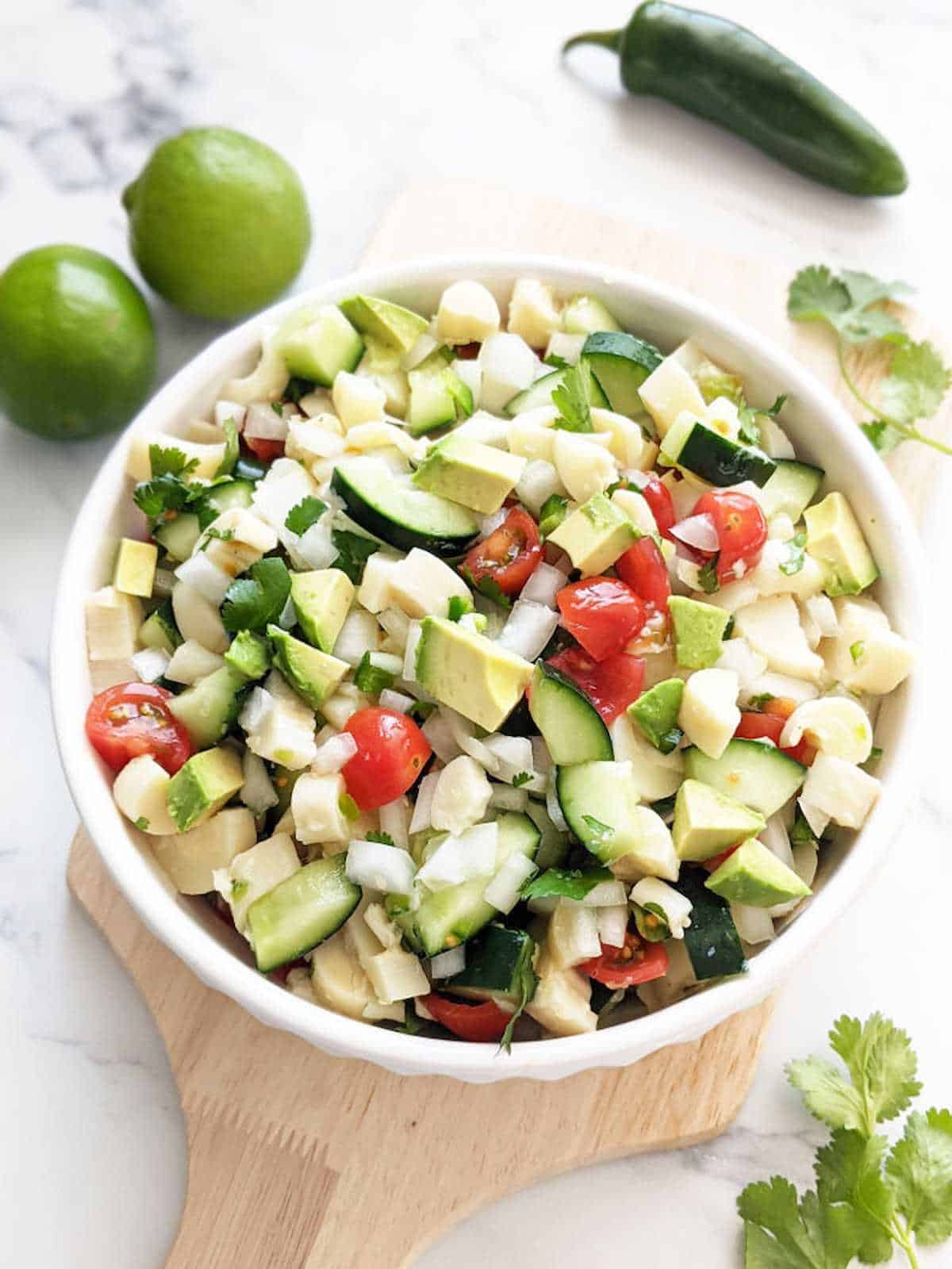 Vegan ceviche made with hearts of palm in a bowl sitting on a wooden serving platter.