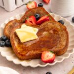 Two slices of vegan French toast with butter and fruit.