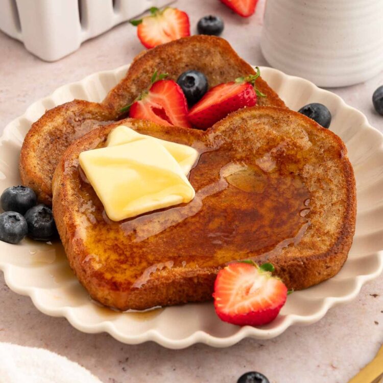 Two slices of vegan French toast with butter and fruit.