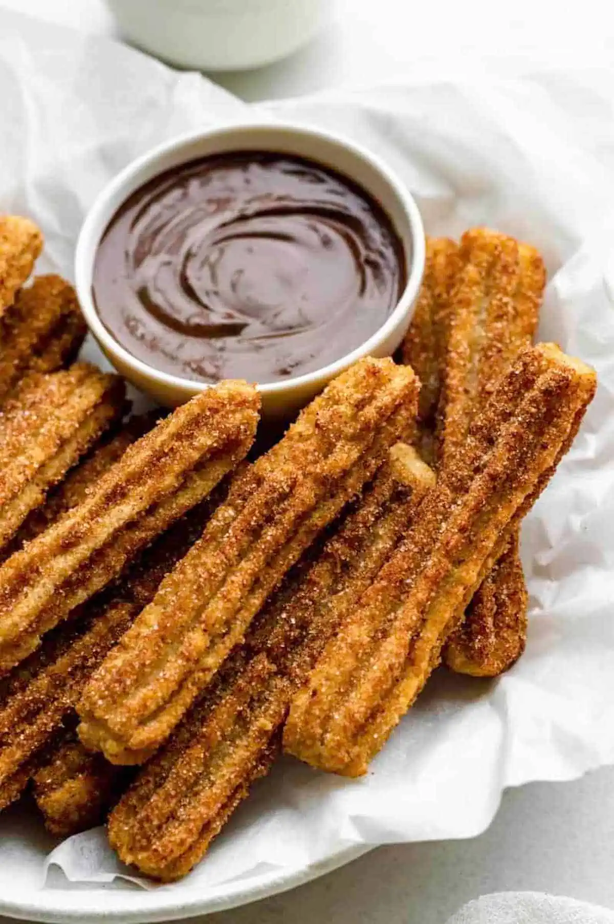 Vegan churros next to a bowl of sweet dipping sauce.