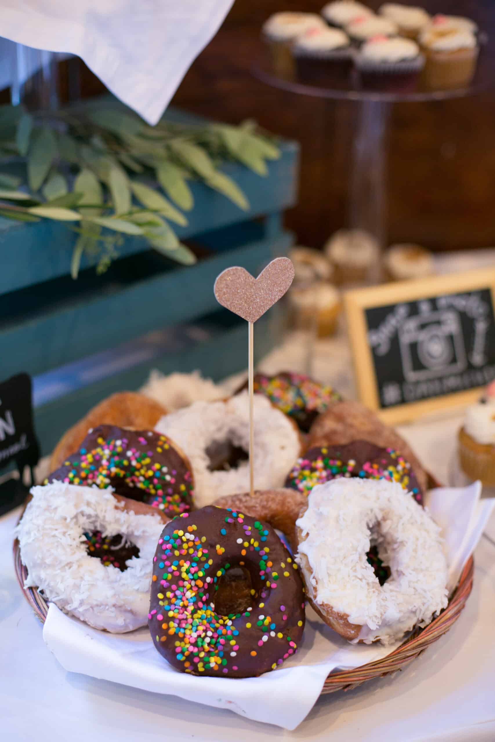 Close-up of vegan donuts with frosting and sprinkles on a plate.