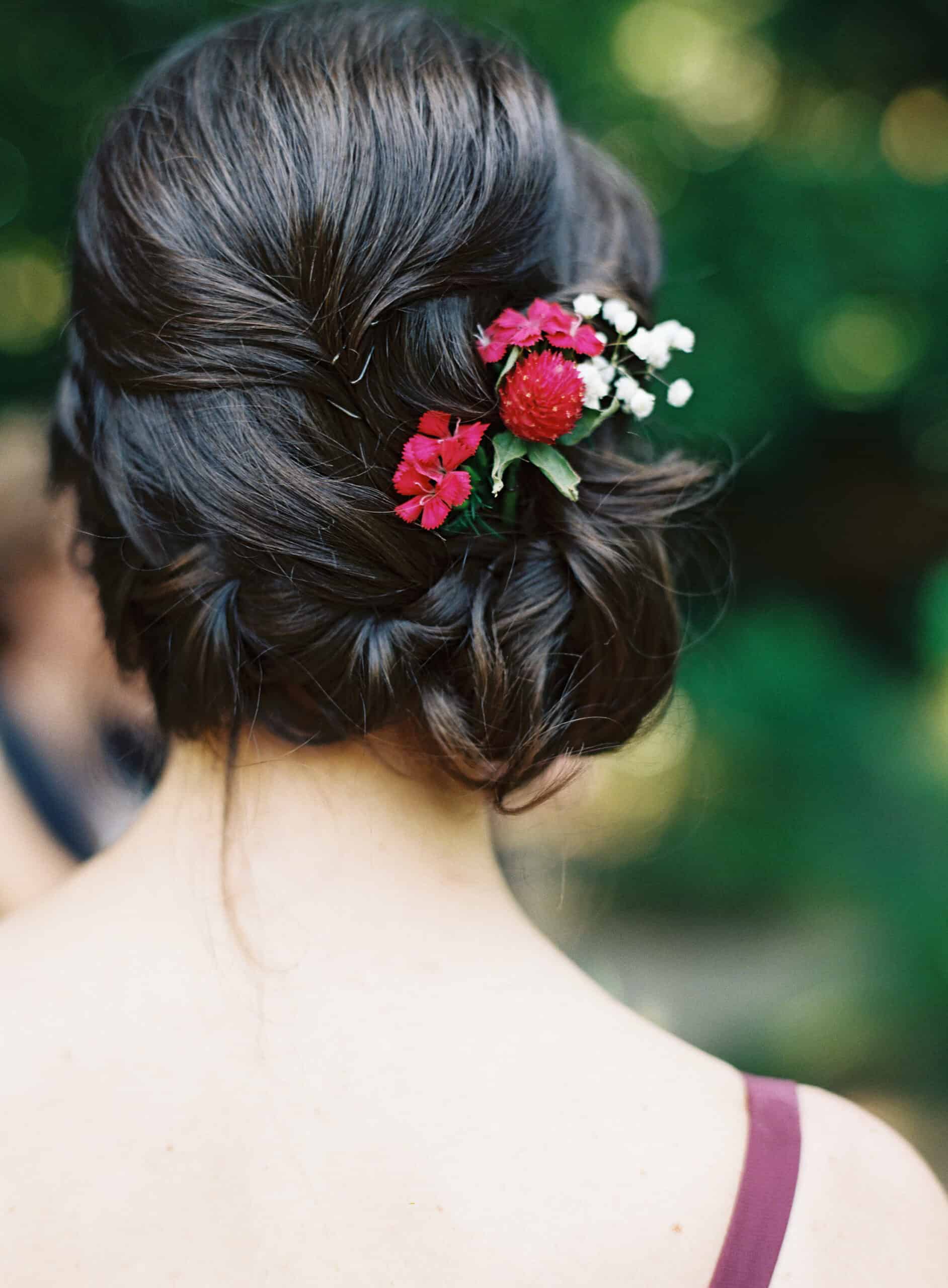 Bridesmaid with an elegant updo and fresh flower hairpiece at a vegan wedding.