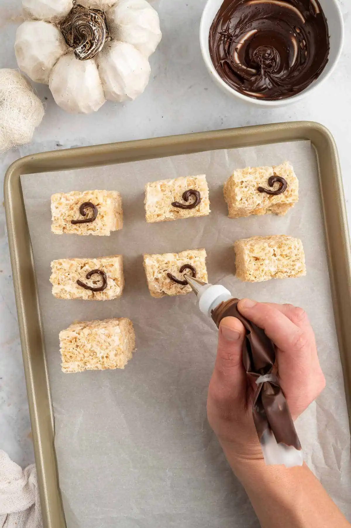 Piping chocolate tails onto the rice krispies.