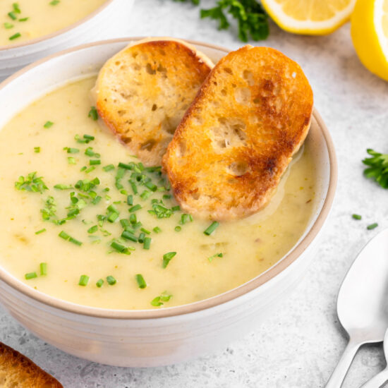 Vegan potato leek soup in a bowl with a couple slices of crusty bread.