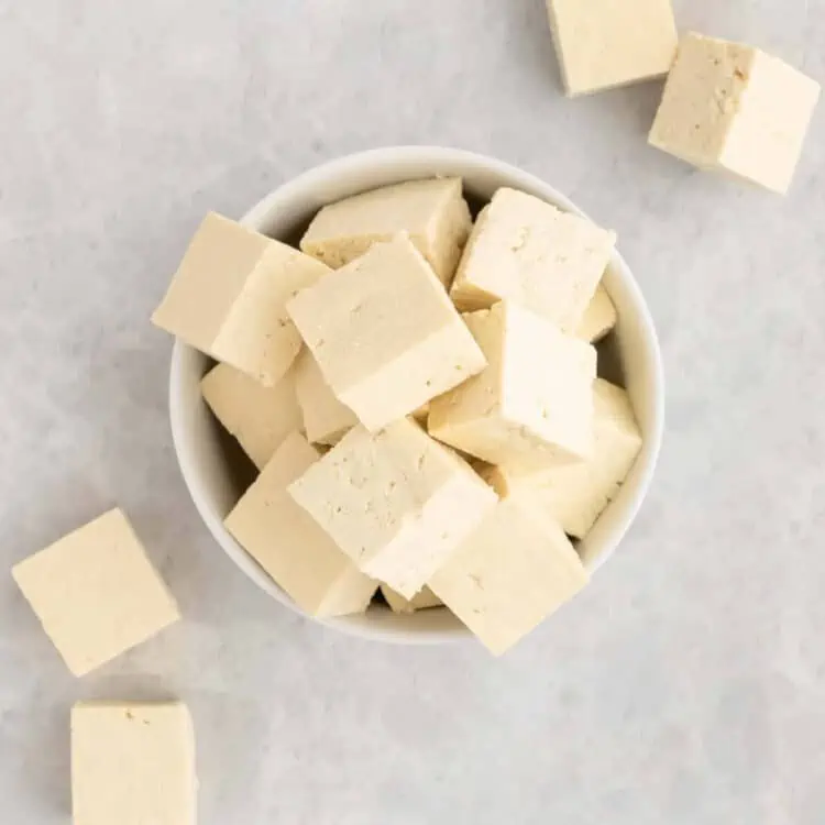 Tofu sliced into cubes in bowl.