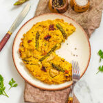Vegan frittata on a serving platter with a slice missing.