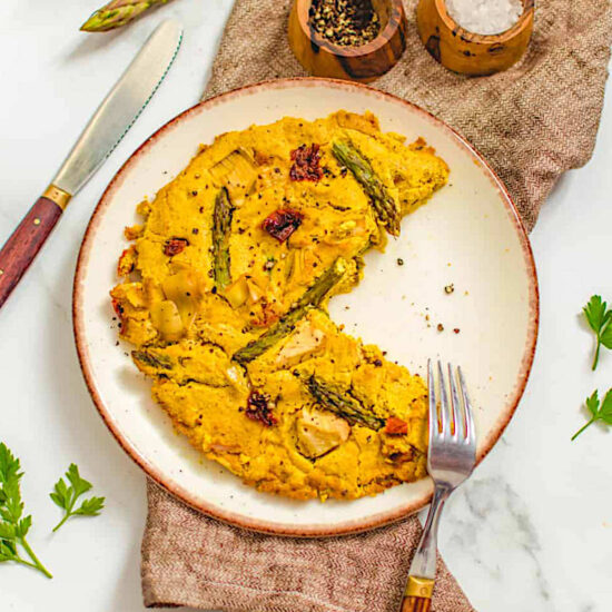 Vegan frittata on a serving platter with a slice missing.