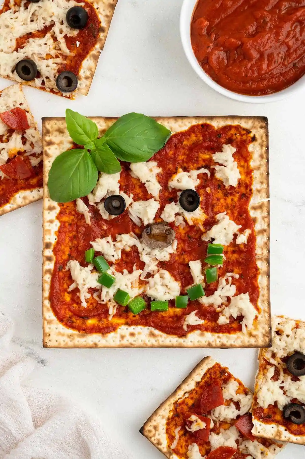 Matzah pizza with veggie toppings arranged to look like a smiley face.