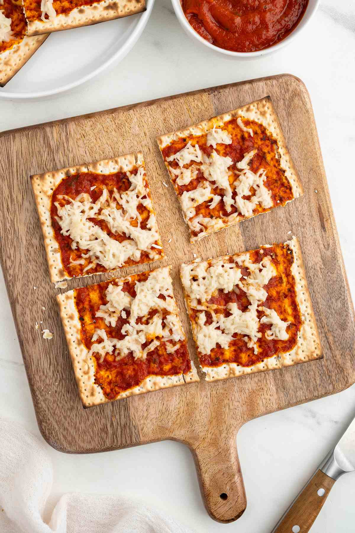 Cheese matzah pizza cut into four slices on a wooden pizza tray.