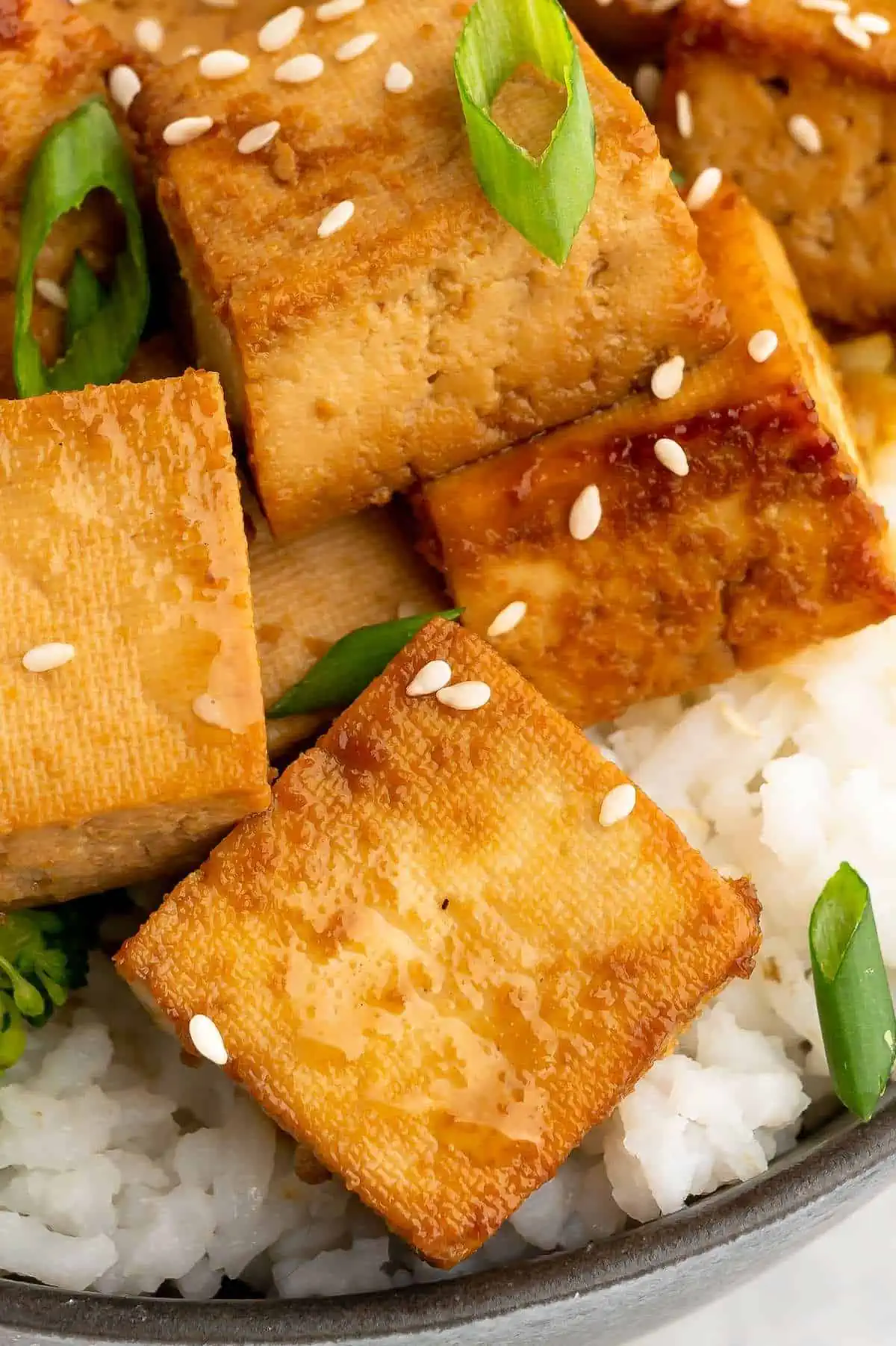 Up close of golden tofu cubes that have bee marinated and cooked.