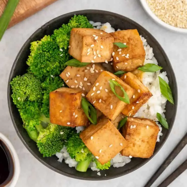 Marinated tofu served in a bowl over rice and broccoli.