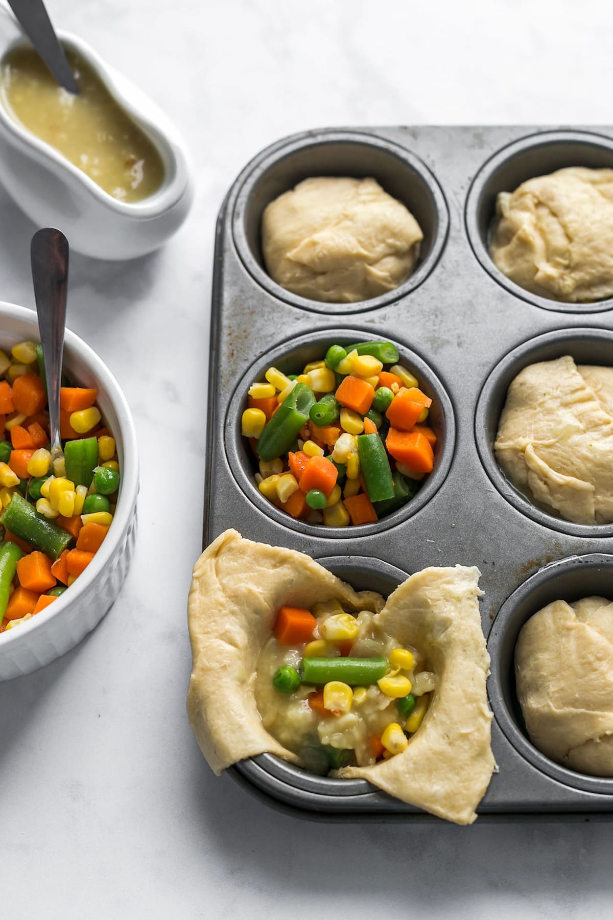 A muffin tin with the crescent roll dough in each muffin cup and the filling added on top.