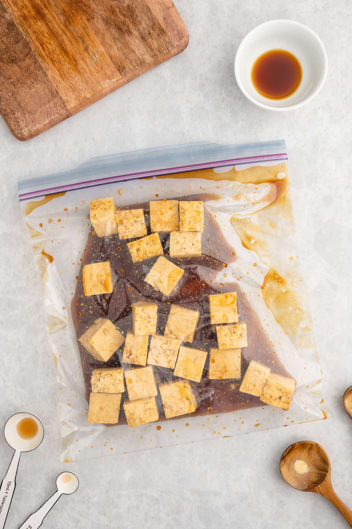 Tofu cubes marinating in plastic food-safe bag.