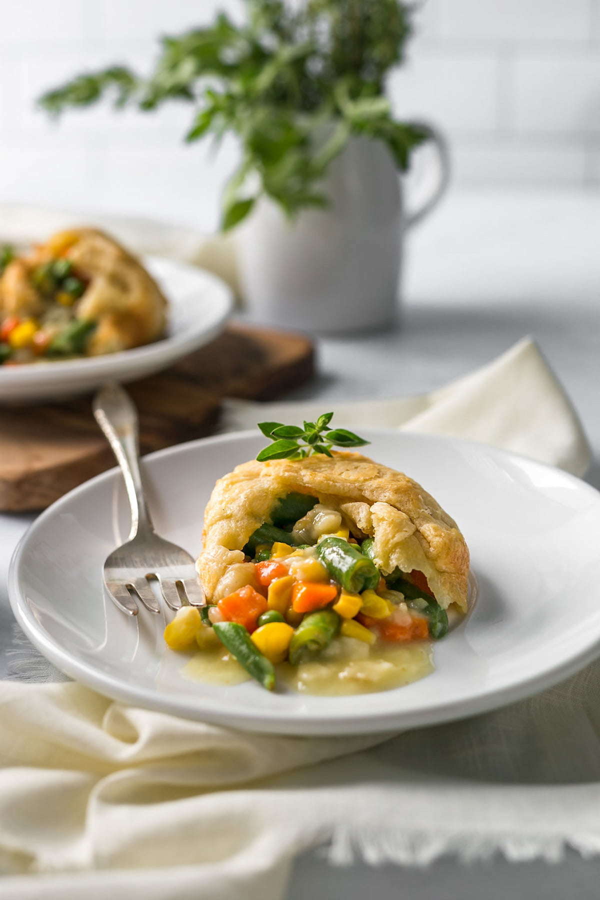 Vegan pot pie on a plate with the vegetable filling spilling out.