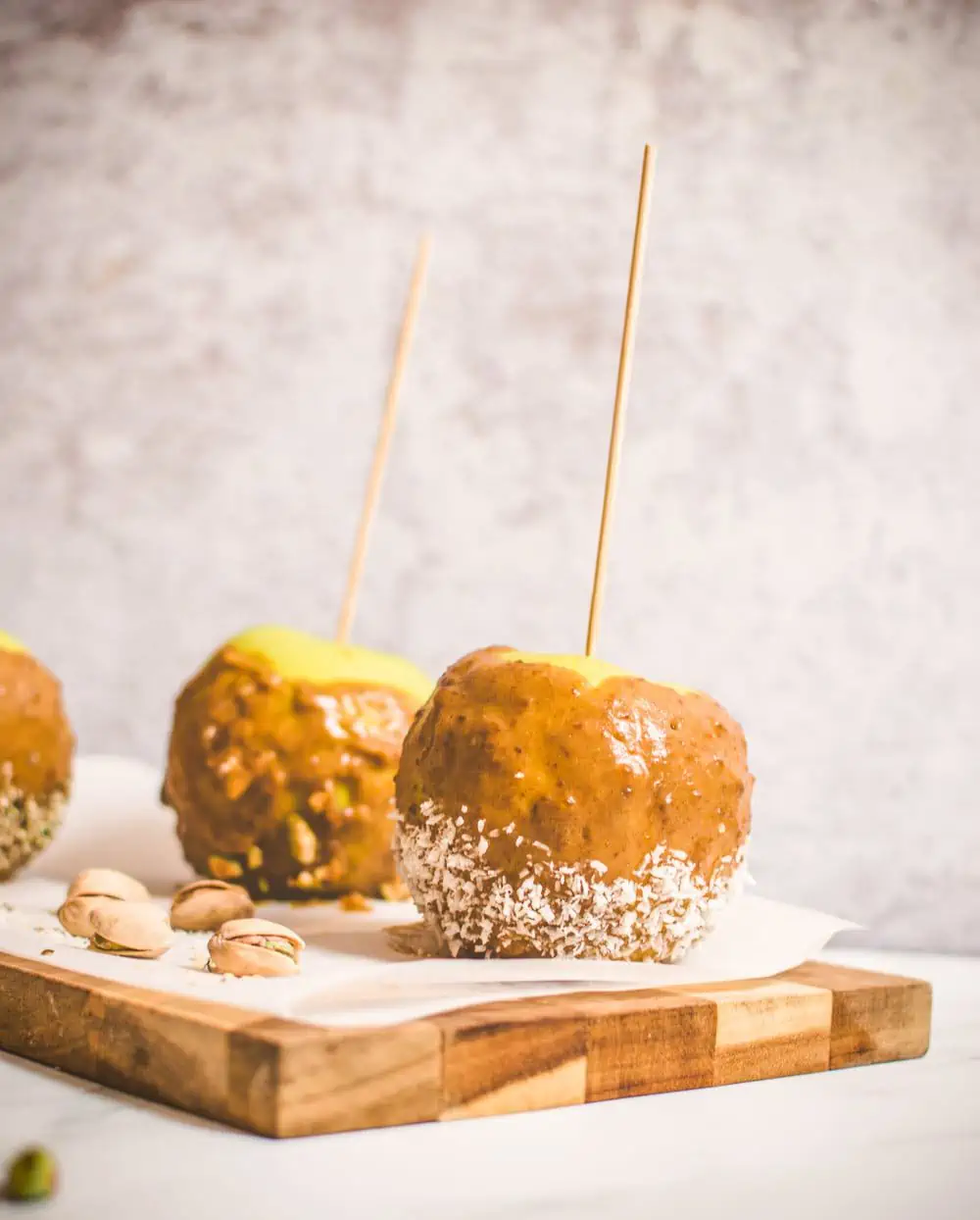 Homemade Vegan Caramel Apples on sticks on a boars with Pistachios
