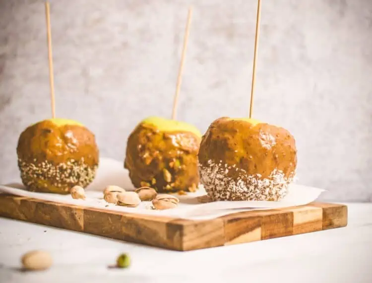 Homemade Vegan Caramel Apples on sticks on a boars with Pistachios