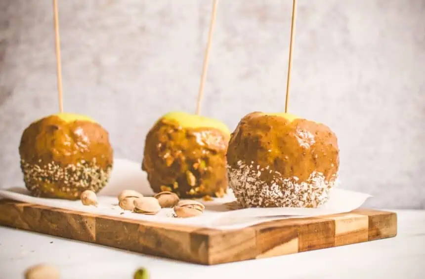 Homemade Vegan Caramel Apples on sticks on a boars with Pistachios