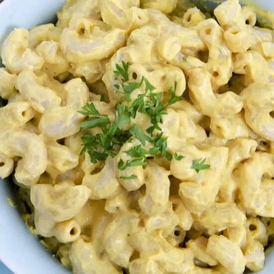 Bowl of vegan mac and cheese without cashews, topped with chopped parsley.