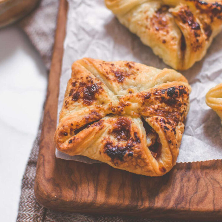 Apple vegan hand pie sitting on a cutting board covered with parchment paper.