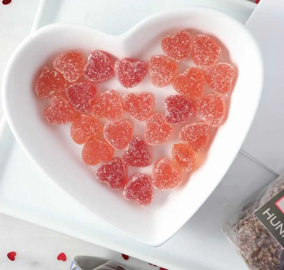 A heart-shaped bowl full of gummy heart-shaped candies.