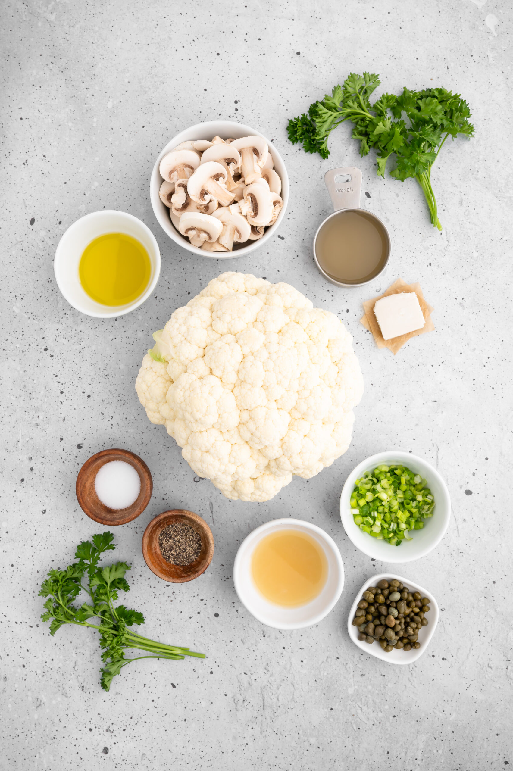 Ingredients for cauliflower steaks arranged on a countertop in various bowls.