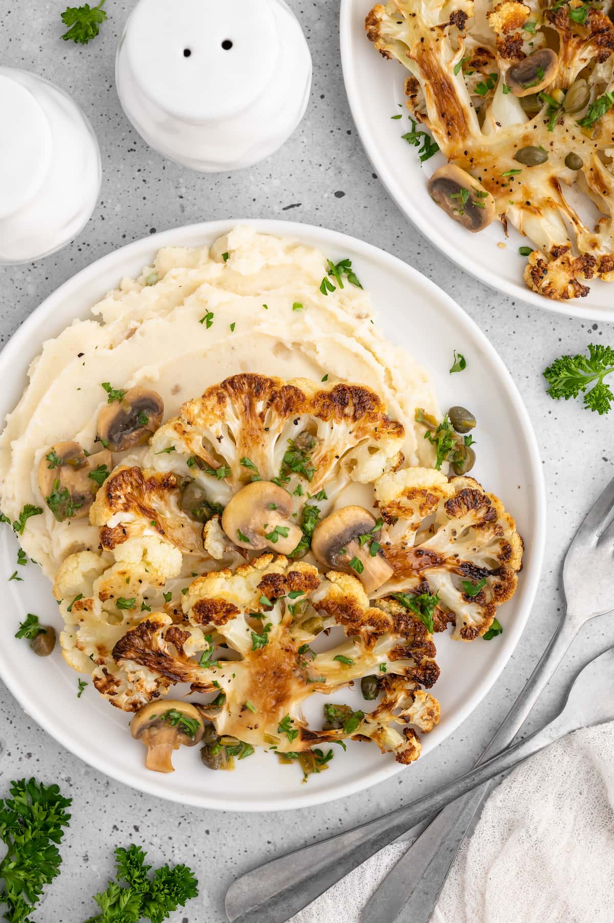 Vegan cauliflower steaks on a bed of mashed potatoes.