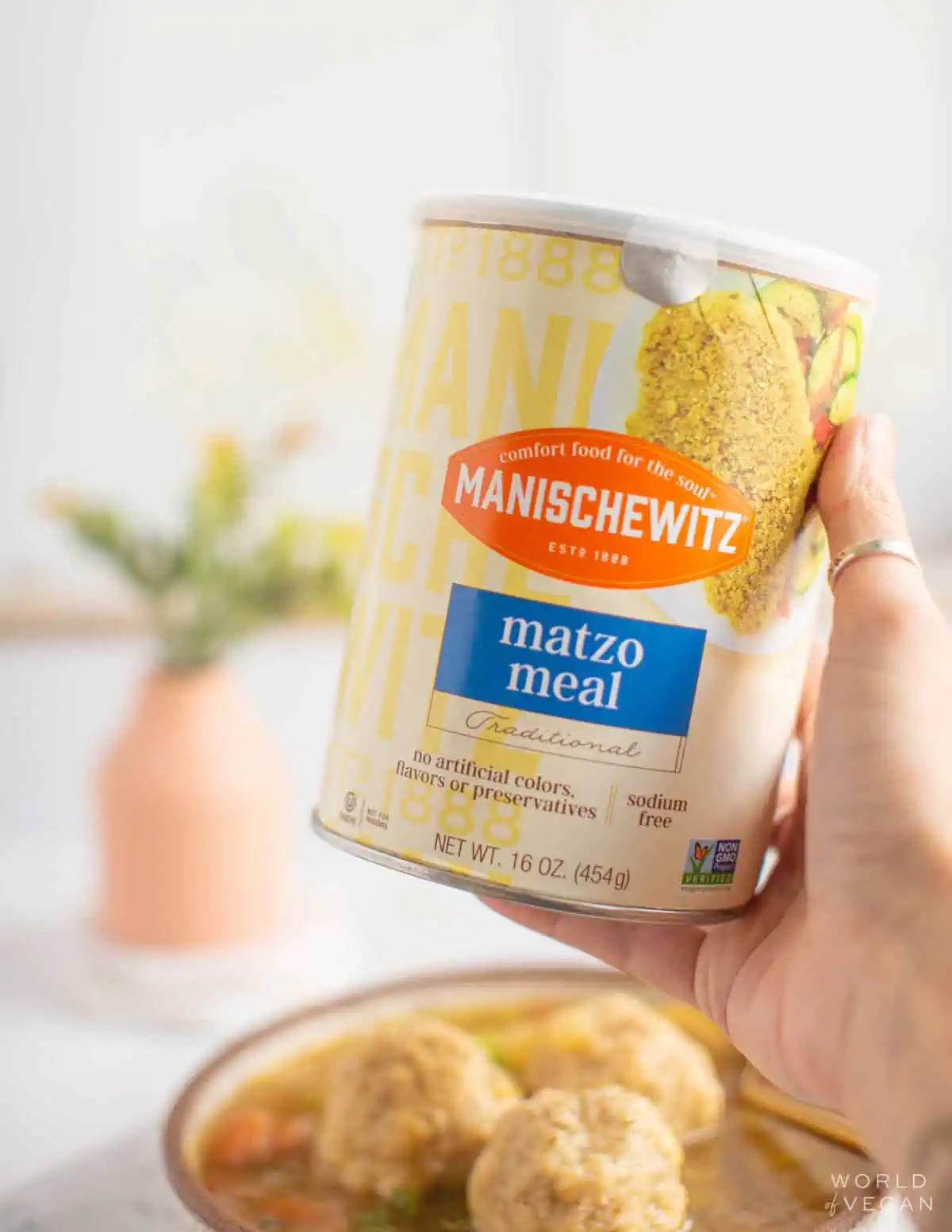 Woman holding up a container of matzo meal from the brand Manischewitz. 