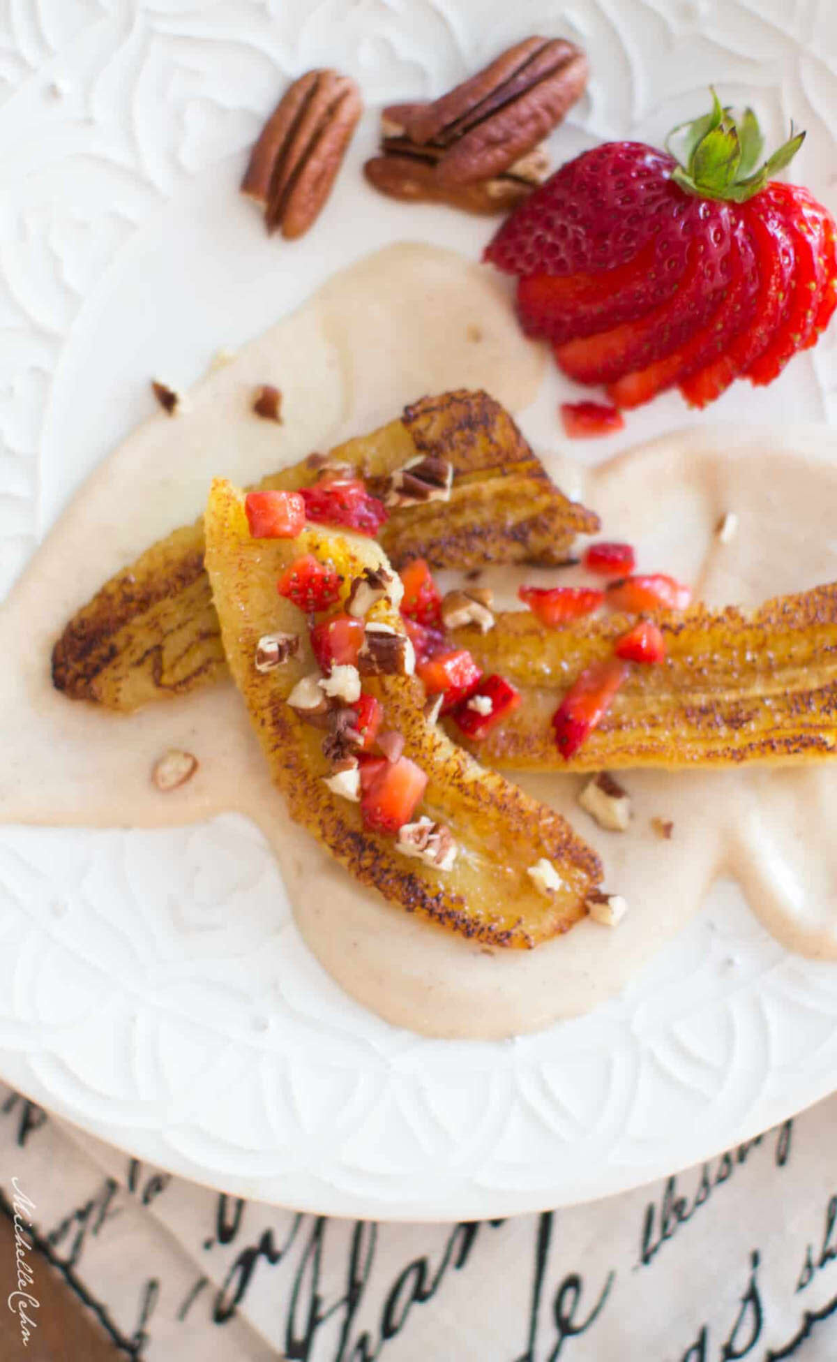 Golden cinnamon pan fried banana slices on a plate, served over a maple cream sauce.