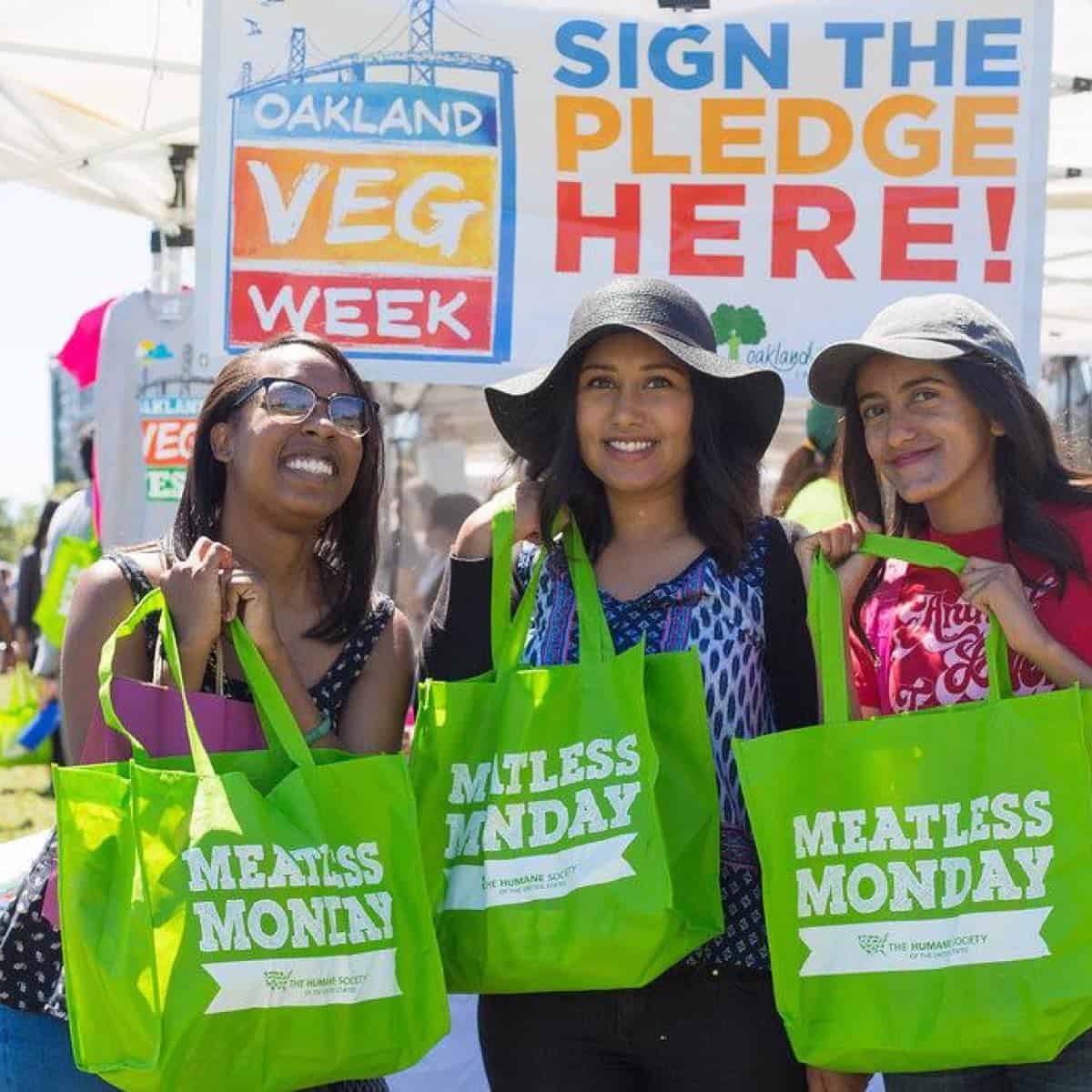 three girls holding meatless monday bags at oakland vegfest