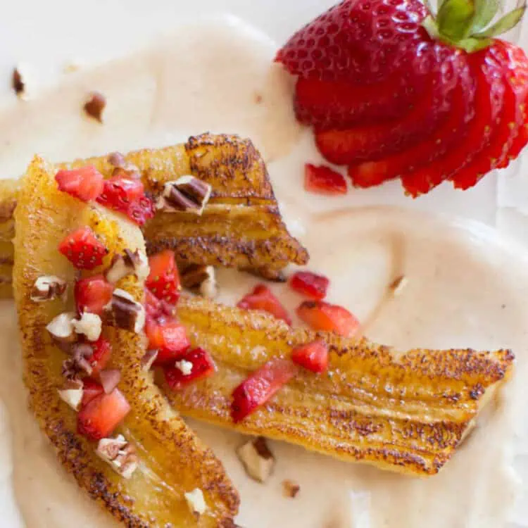 Golden cinnamon pan fried banana slices on a plate, served over a maple cream sauce.