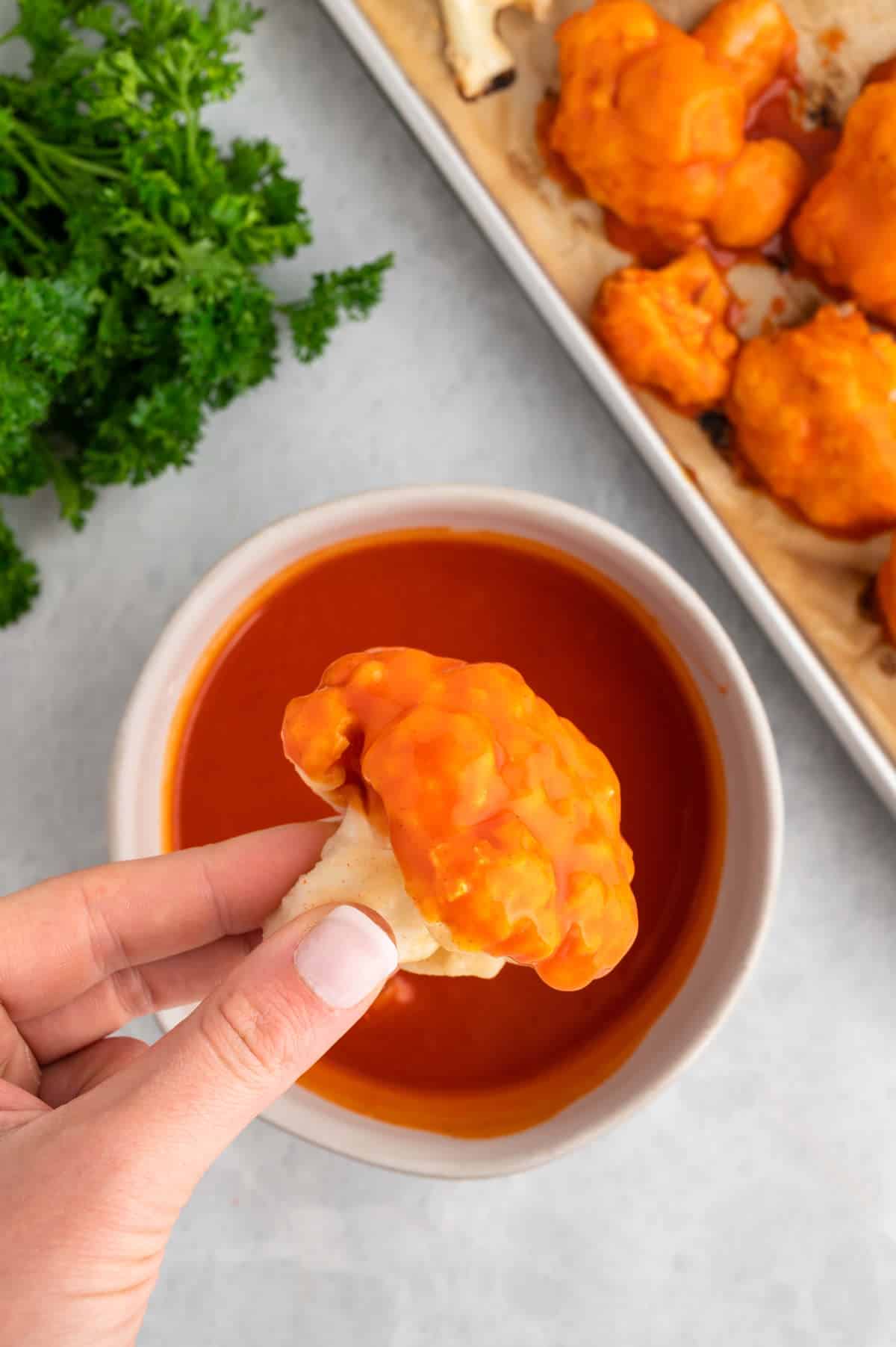 Vegan cauliflower wing dipped in hot sauce.