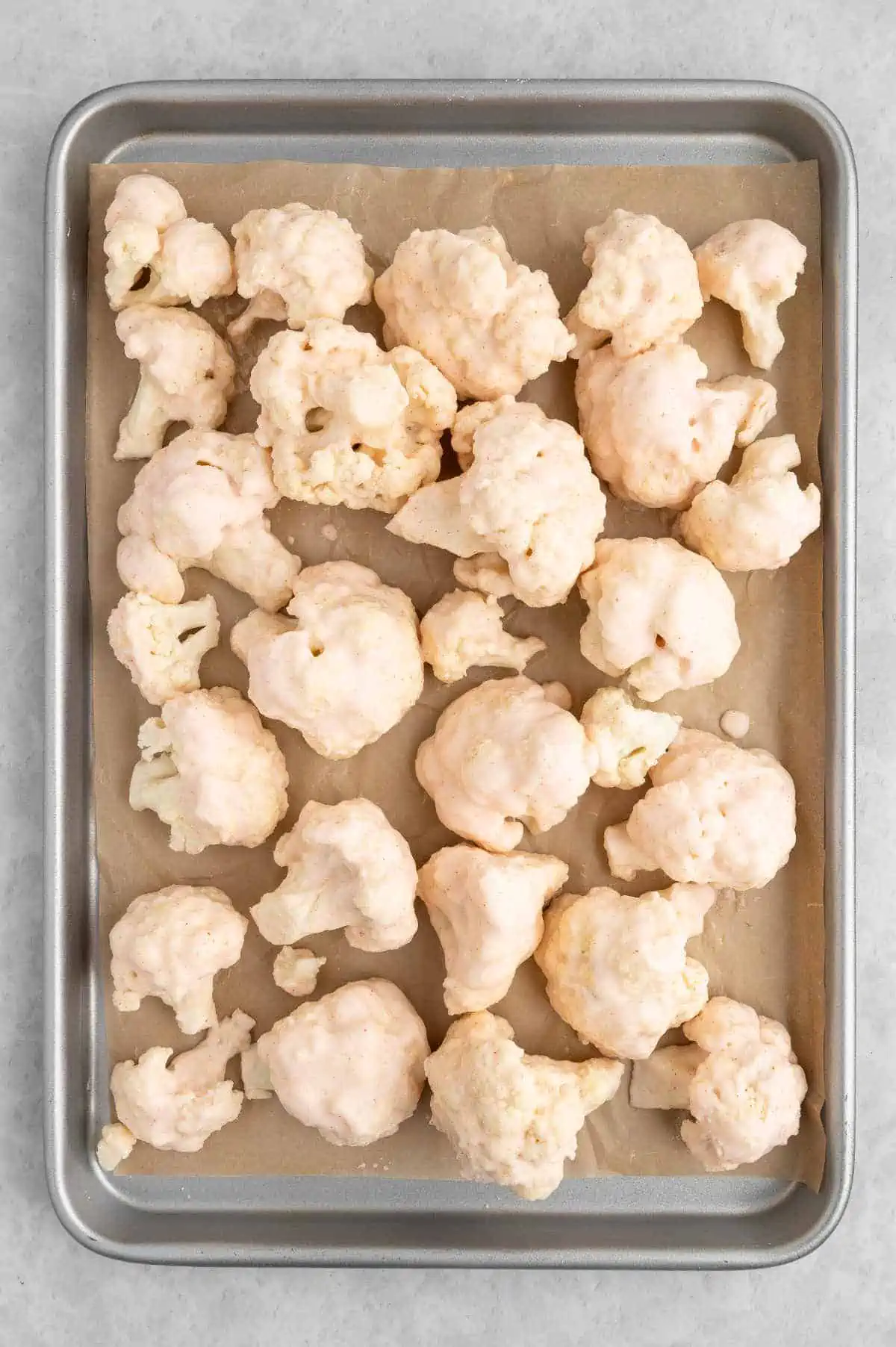 Buffalo cauliflower dipped in batter and arranged on baking tray.