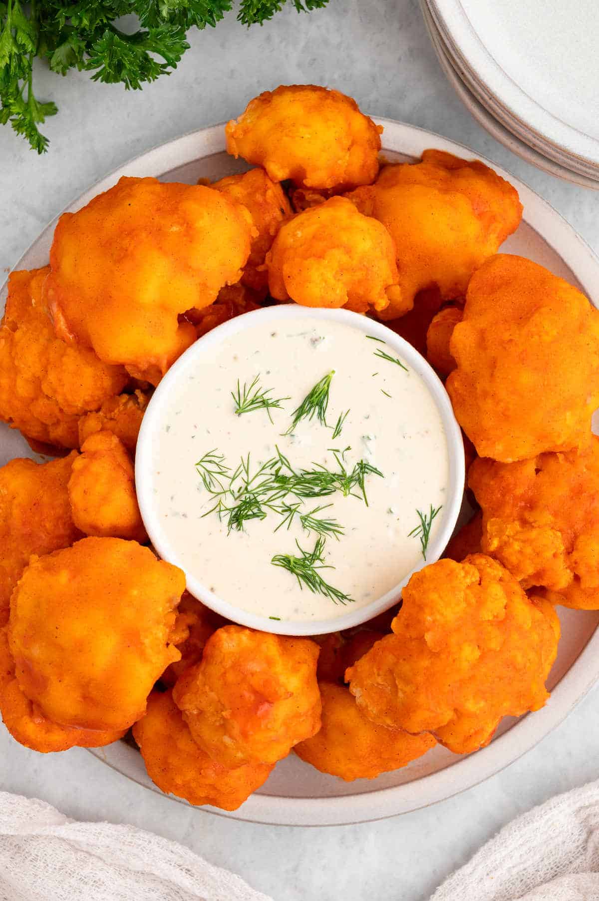 Vegan buffalo cauliflower wings on a plate with vegan ranch dip.