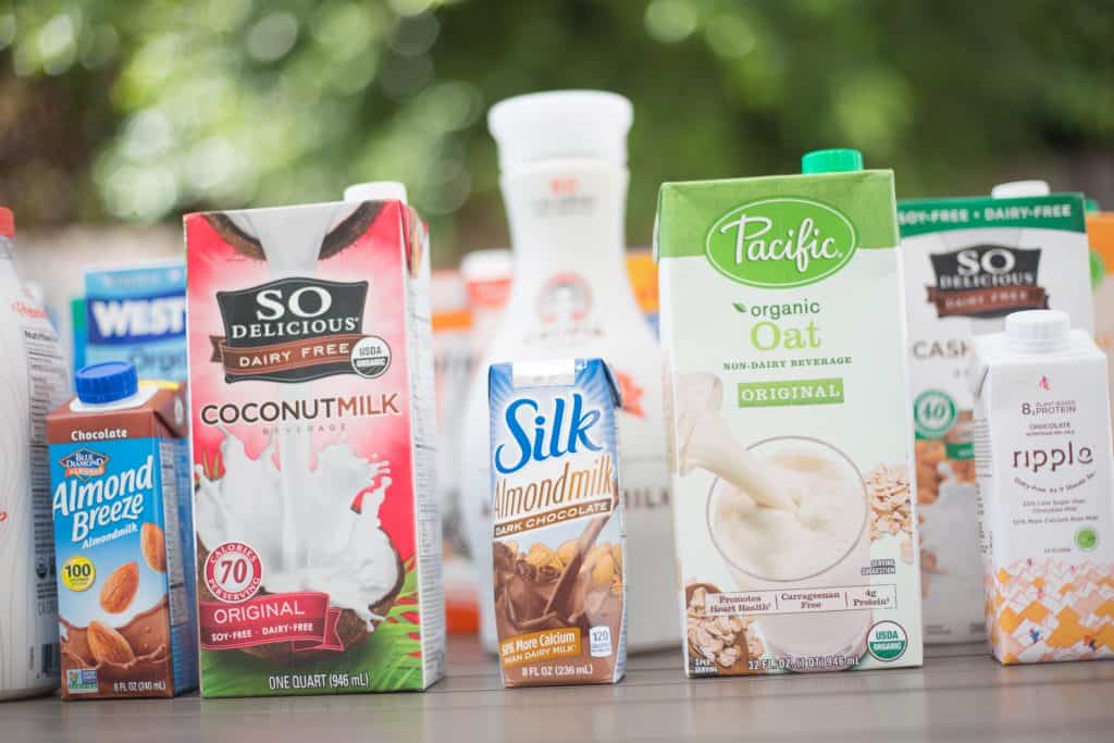 milk cartons from different vegan milk brands lined up including so delicious silk ripple and almond breeze