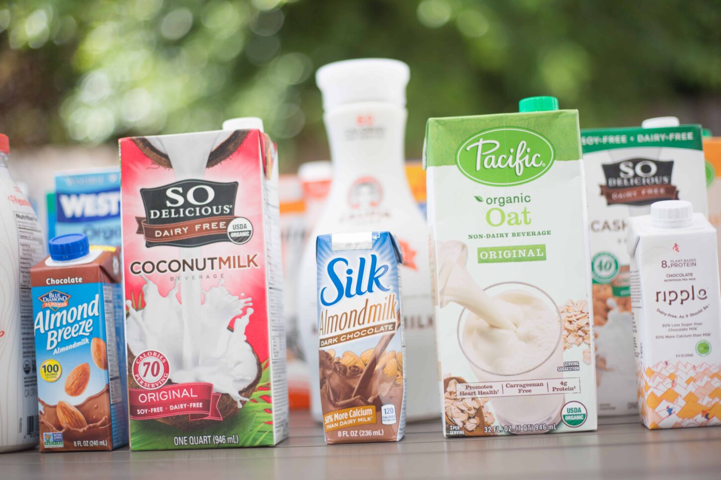 Various vegan milk brand cartons in a row.
