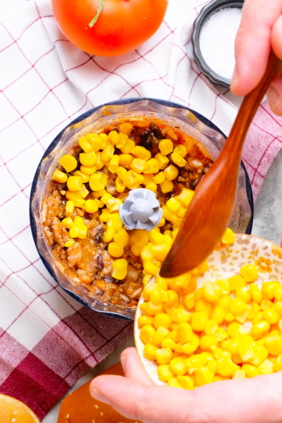 Corn being added to the food processor filled with chipotle black bean mixture.