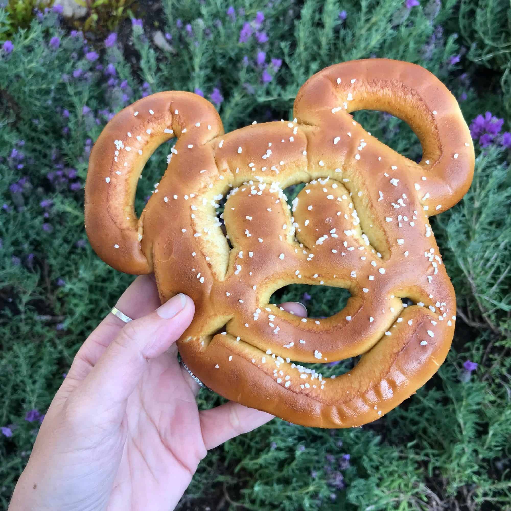 A hand holding a Mickey Mouse pretzel.