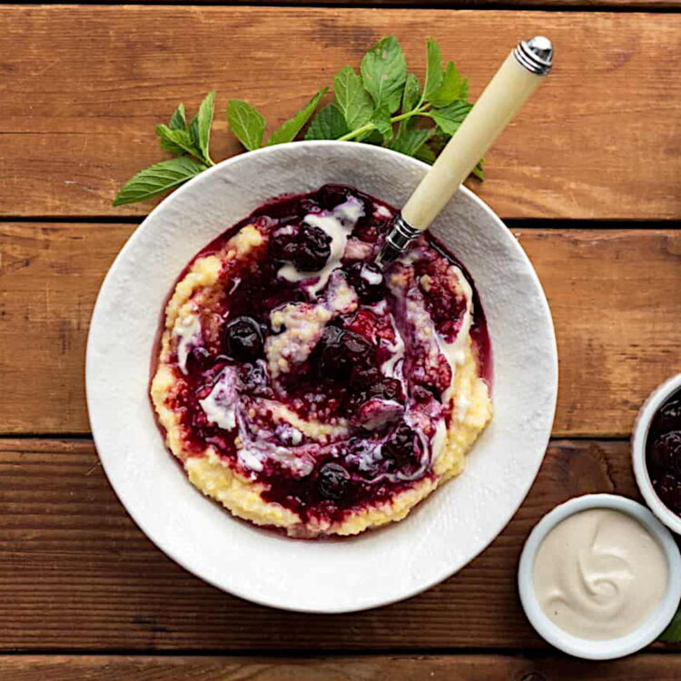 Creamy berry breakfast polenta in a bowl with a spoon.