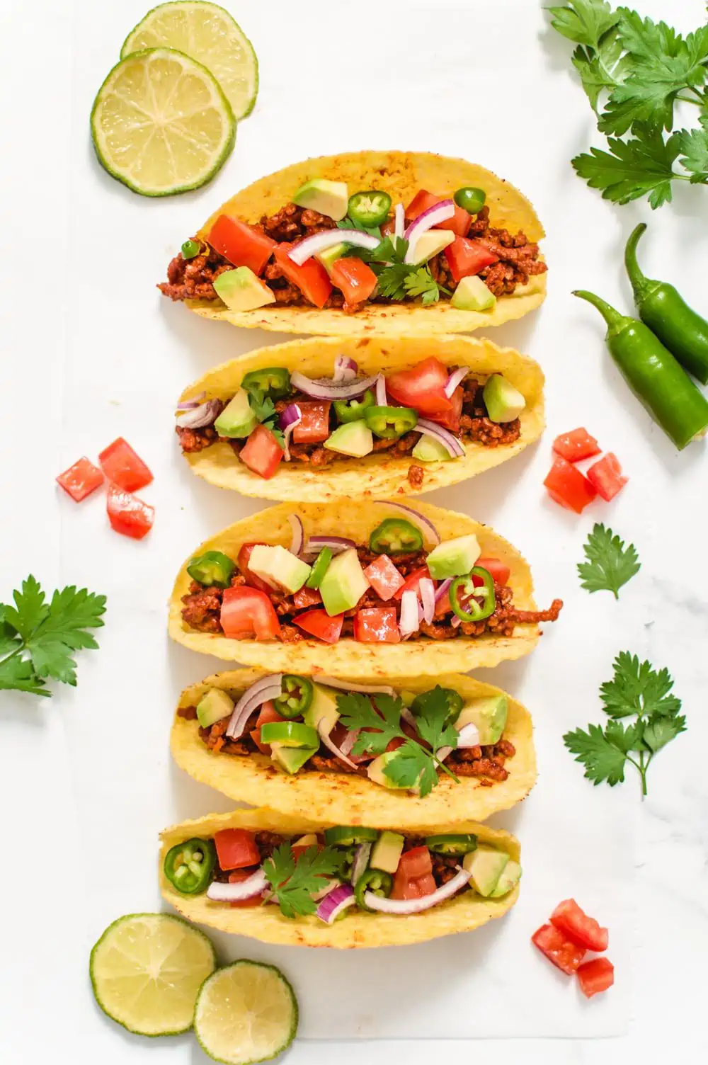 Beefy Lover's Vegan Tacos in crunchy shells surrounded by various toppings.
