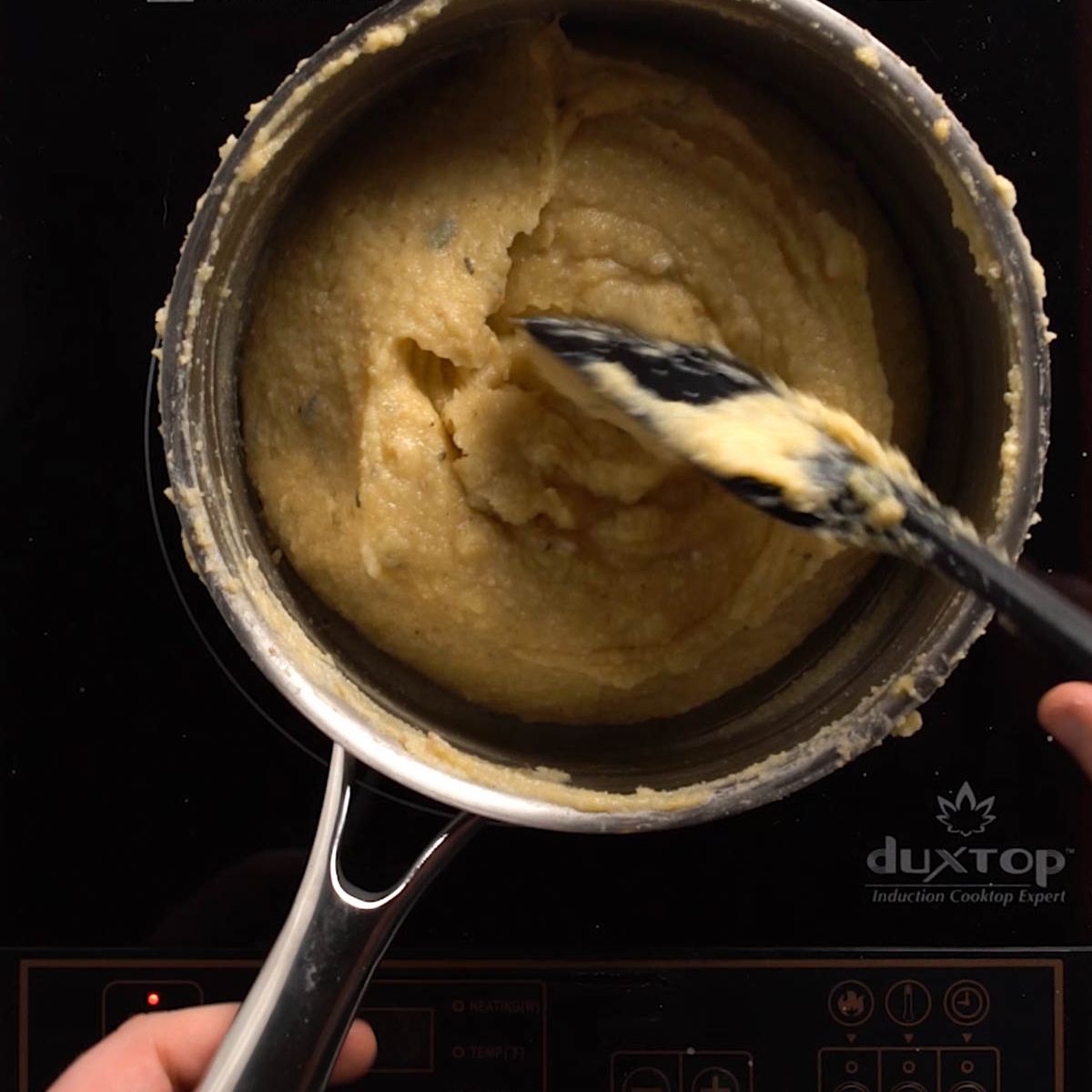 Polenta being stirred in a saucepan.
