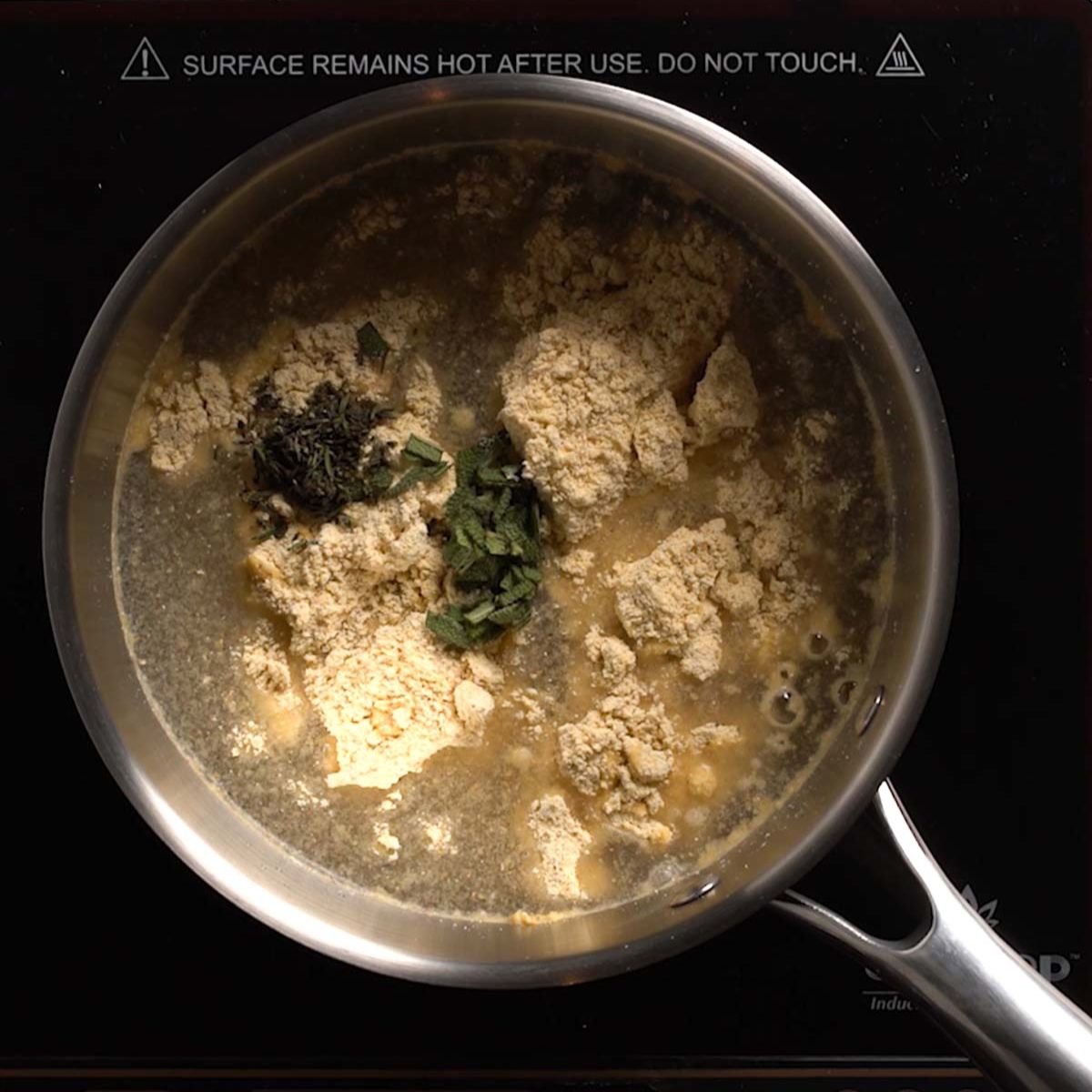 Polenta, herbs, and water in a saucepan.