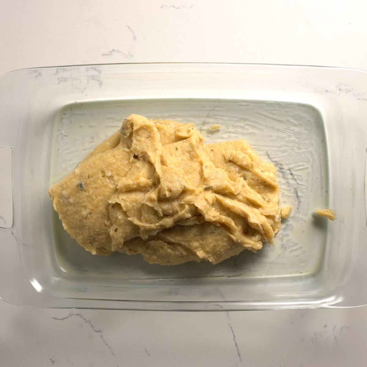 Polenta batter in a glass baking dish.