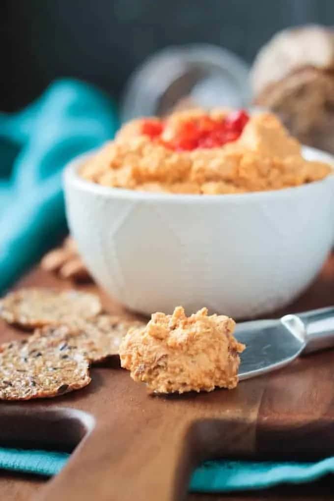 vegan cheddar spread in a bowl and on a knife with crackers