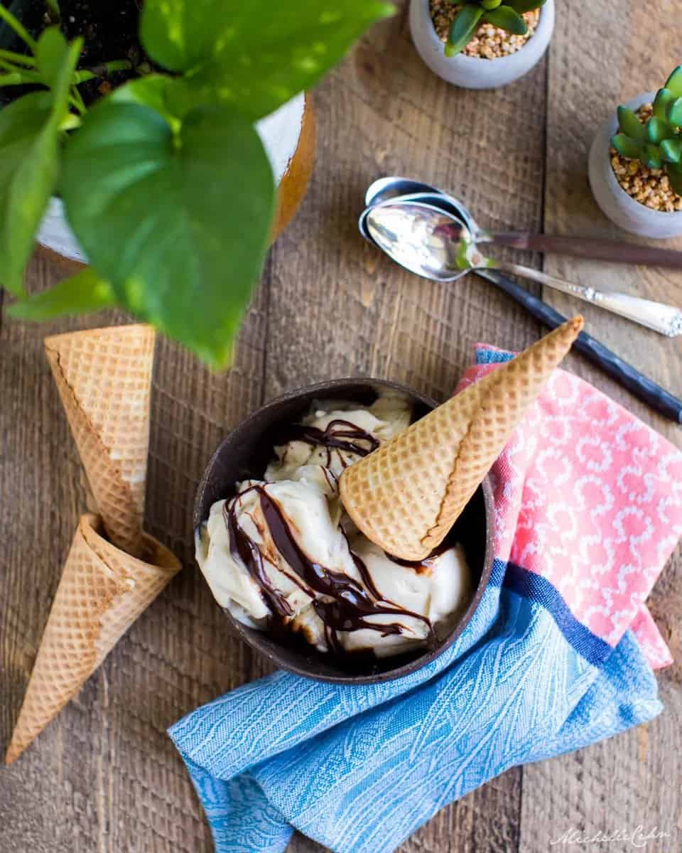 banana nice cream in a bowl with chocolate drizzle and a cone on it