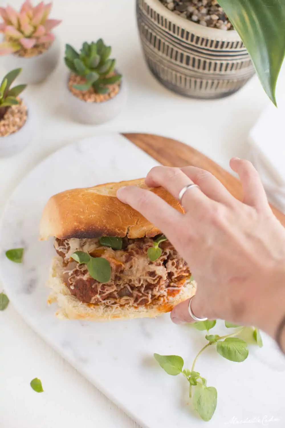 Vegan holding a huge meaty plant-based meatball sub sandwich.
