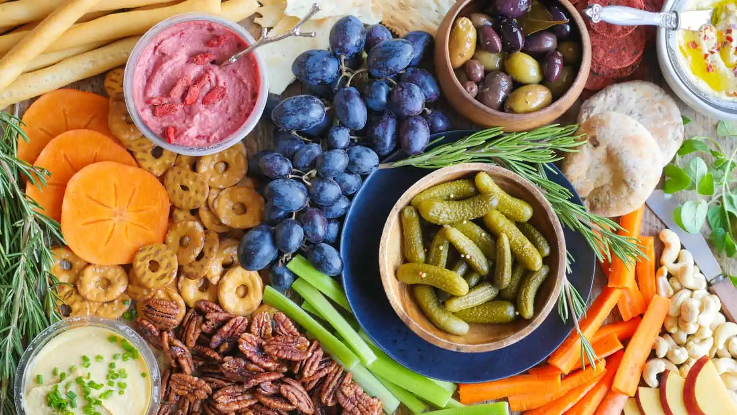 A vegan hummus board filled with fruits, nuts, veggies, and various bowls of hummus.