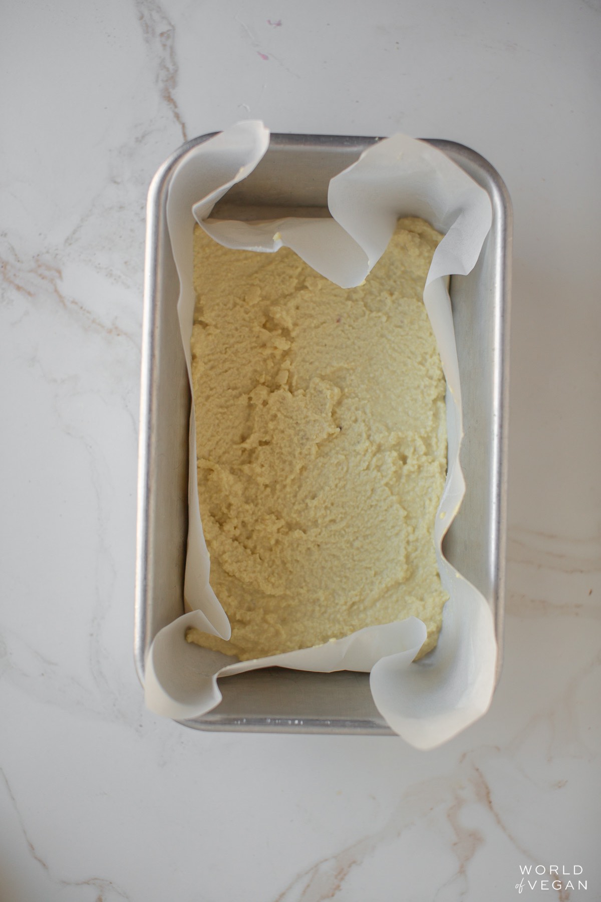 Almond cheese blended in a loaf pan baking dish lined with parchment.