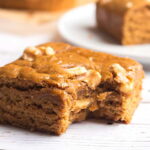 Vegan blondie with maple walnut flavor and a bite taken out of a corner to show the chewy interior.