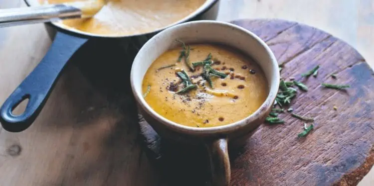 gluten-free butternut squash soup in a bowl with herb garnish